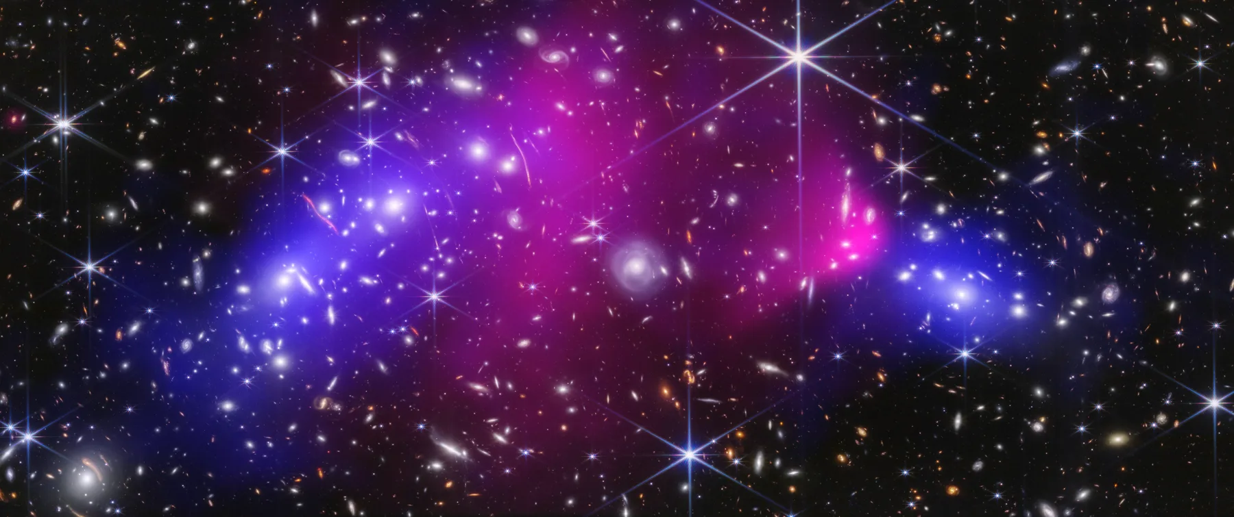 The Bullet Cluster (1E 0657-56) in a 2025 NASA Webb and Chandra composite: hot X-ray gas (pink) lags behind the mass mapped by gravitational lensing (blue)